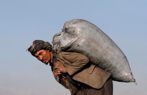 An Afghan carries a sack of coal on his back outside Kabul
